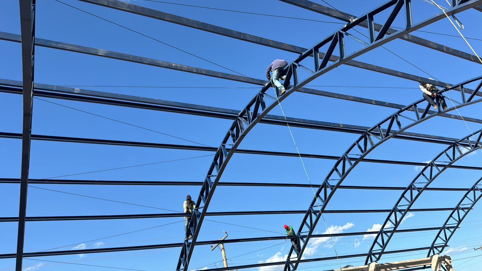 Equipe executando montagem de estrutura metálica em altura