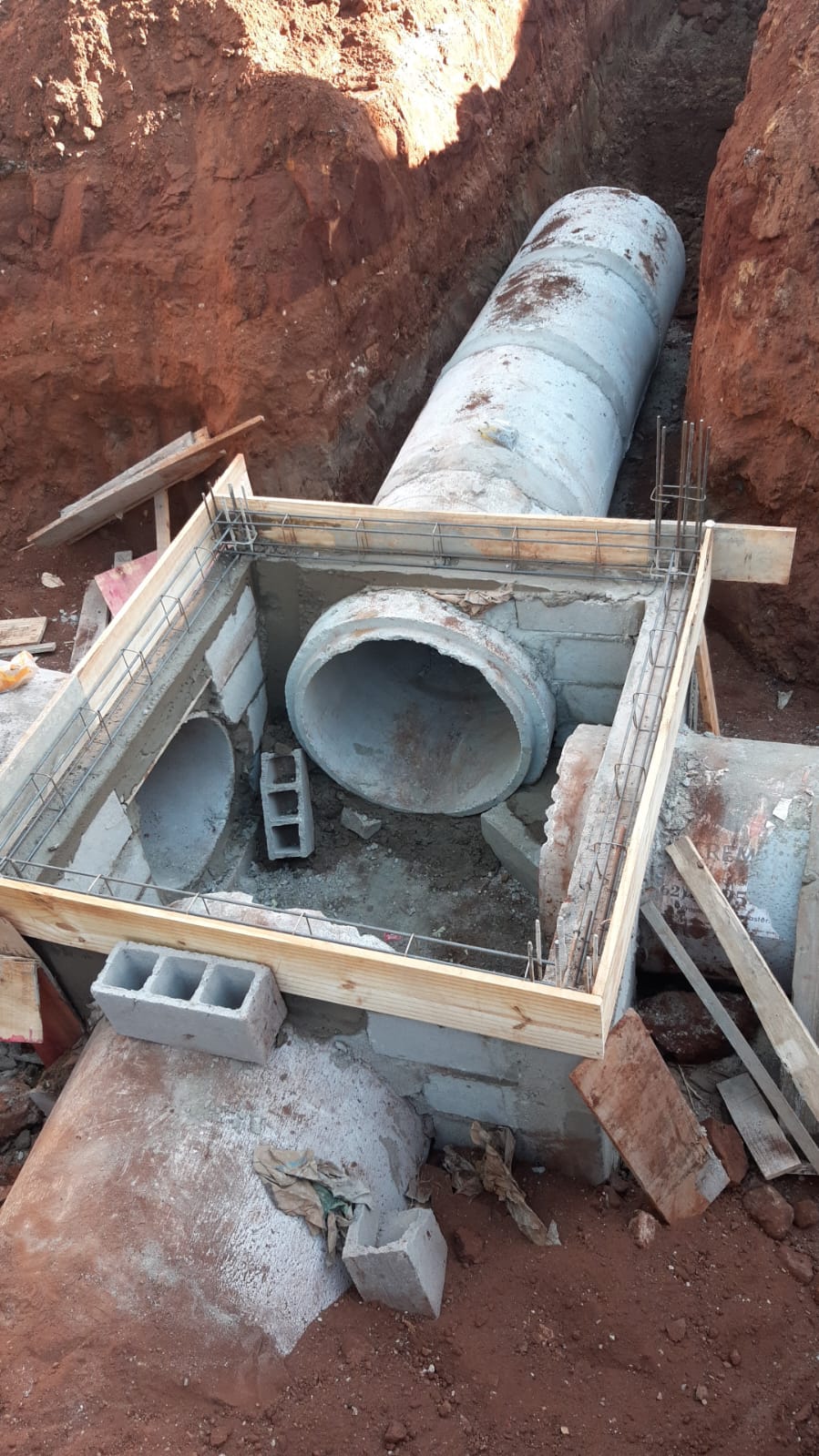 Execução de drenagem com tubulação de concreto e caixa em construção